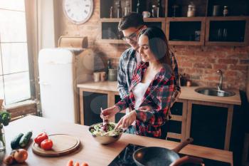 Love couple cooking on the kitchen, vegetable salad preparation. Fresh diet food. Man and woman prepares romantic dinner