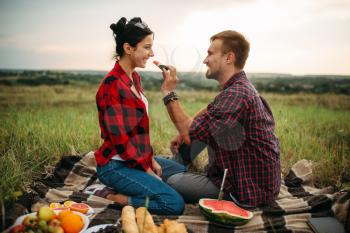 Love couple hugs, picnic in summer field. Romantic junket, man and woman leisure together, happy family weekend
