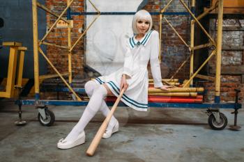Pretty anime style blonde girl with baseball bat. Cosplay fashion, asian culture, doll in uniform, cute woman with makeup in the factory shop