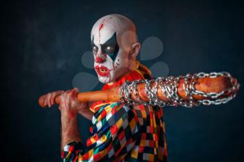 Mad bloody clown with baseball bat. Man with scary makeup in halloween costume