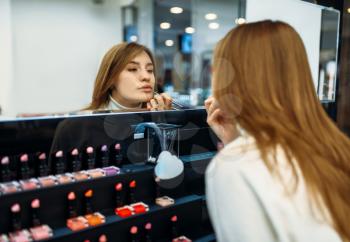Female client testing lip liner in the make-up shop. Cosmetics choosing in beauty store, makeup salon