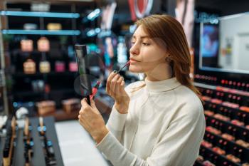 Female customer testing lip liner in the makeup shop. Cosmetics choosing in beauty store, make-up