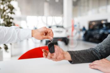 Manager gives to woman the key to the new car in showroom. Female customer buying vehicle in dealership, automobile sale