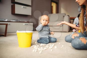 Little kid spilled popcorn on the floor, motherhood problems. Sad mom and son together at home, parenthood