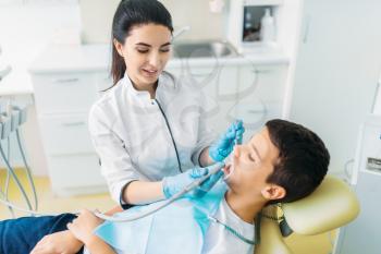 Caries removal procedure, pediatric dentistry, children stomatology. Female dentist drilling teeth, dental clinic