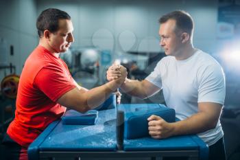 Two arm wrestlers prepares for the battle at the table with pins, workout before wrestling competition. Wrestle challenge, power sport