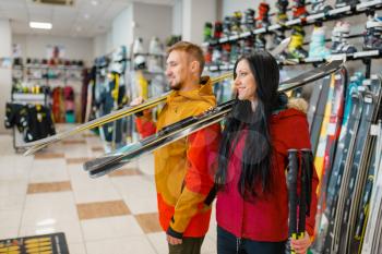 Couple with skis in hands, shopping in sports shop. Winter season extreme lifestyle, active leisure store, customers buying skiing equipment