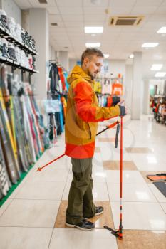 Man at the showcase choosing ski poles, shopping in sports shop. Winter season extreme lifestyle, active leisure store, customer buying skiing equipment