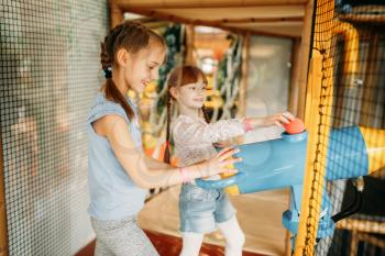 Two little girls plays air gun in children game center. Excited childs having fun on playground indoors. Kids playing in amusement centre