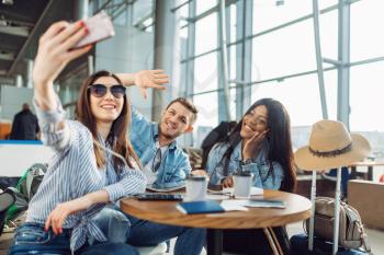 Three tourists makes selfie on phone in airport. Passengers with baggage look forward to flight in air terminal, happy friends on journey, summer travel on vacation
