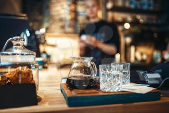 Glasses with black coffee and filtered water, male barista at cafe or bar counter on background. Professional espresso preparation by bartender in cafeteria, barman occupation