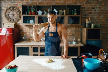 Young husband in underwear cooking on the kitchen. Naked man in apron preparing breakfast at home, food preparation without clothes