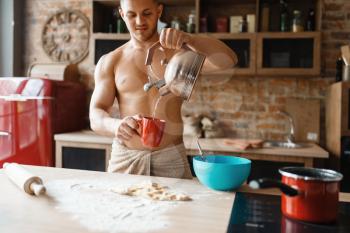 Nude man cooking romantic dinner on the kitchen. Naked male person preparing breakfast at home, food preparation without clothes