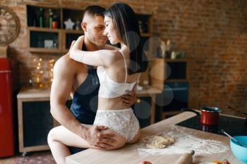 Romantic couple in underwear cooking on the kitchen together. Naked man and woman preparing breakfast at home, food preparation without clothes
