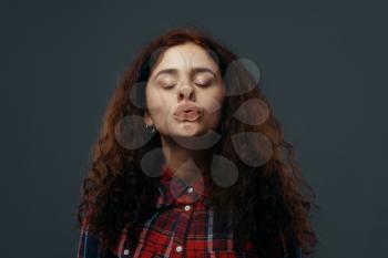 Young woman's crazy face crushed on transparent glass. Female person with pressed grimace standing at the showcase, humor, uncomfortable looking, facial fun