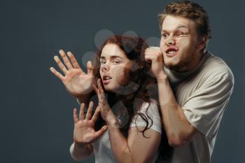 Young couple faces crushed on transparent glass, funny emotion. Man and woman with pressed grimaces standing at the showcase, humor, uncomfortable looking