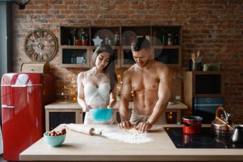 Young couple in underwear cooking on the kitchen. Naked man and woman preparing breakfast at home, food preparation without clothes