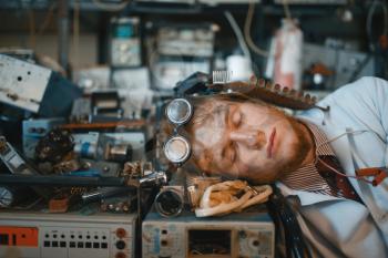 Strange engineer sleeping on devices in laboratory. Electrical testing tools on background. Lab equipment, engineering workshop