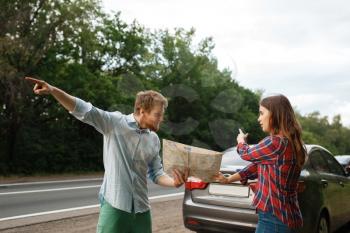 Car tourists with map having quarrel, road travel. Couple on vehicle got lost, searching for the right way. Man and woman on vacations, auto trip