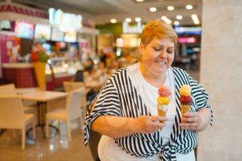 Fat woman holding ice cream in fastfood mall restaurant, unhealthy food. Overweight female person with ice-cream, obesity problem