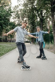 Roller skating, two male skaters rolling in summer park. Urban roller-skating, active extreme sport outdoors, rollerskating