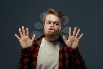 Young man's crazy face and hands crushed on transparent glass. Male person with pressed grimace standing at the showcase, humor, uncomfortable looking, funny emotion