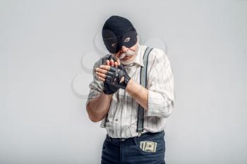 Elderly robber in mask isolated on grey background, gangster. Mature senior in studio, man in old age