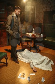 Male detective in coat looking on victim under the cape at the crime scene, retro style. Criminal investigation, inspector is working on a murder, vintage room interior on background