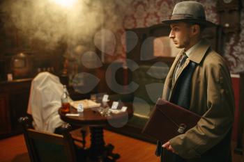 Puzzled detective in coat and hat, victim under the cape at the crime scene, retro style. Criminal investigation, inspector is working on a murder, vintage room interior on background