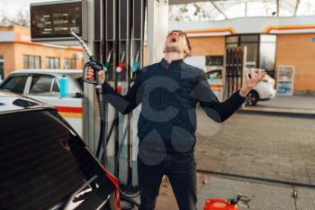 Depressed man cries on gas station, high price on fuel. Petrol fueling, gasoline or diesel refuel service, petroleum refueling