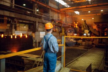 Master looks on steelmaking process in furnace, steel factory, metallurgical or metalworking industry, industrial manufacturing of metal production on mill