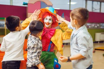 Funny clown, entertainment show with little boys in kindergarten. Birthday celebrating in playroom, baby holiday in playground. Childhood happiness, childish leisure