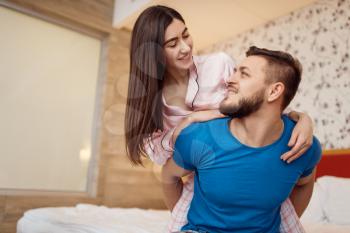 Happy couple in pajamas relaxing in bed at home, good morning. Harmonious relationship in young family. Man and woman resting together in their house, carefree weekend