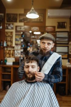 Barber and customer with a mustache, old school beard cutting. Professional barbershop is a trendy occupation. Male hairdresser and client in retro style hairdressing salon