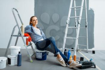 Female house painter relaxing on a lagger. Home repair, happy woman doing appartment renovation, room decoration renovating