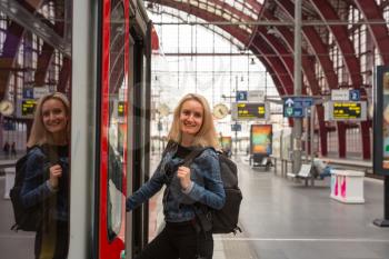 Female tourist with backpack enters the train on railway station platform, travel in Europe. Transportation by european railroads, comfortable tourism