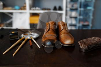 Shoemaker job, footwear repair service concept. Shoemaking workshop, repaired boots and bootmaker tools on the table, cobbler job