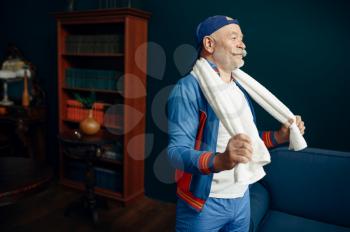 Tired elderly sportsman in uniform after workout at home. Adult male person on fitness training indoors, healthy lifestyle in old age