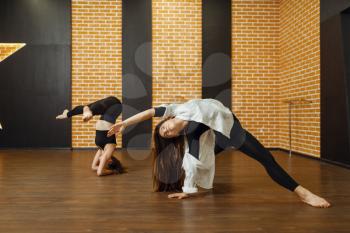 Two contemporary dance performers poses in studio. Female dancers training in class, modern grace dancing, stretching exercise
