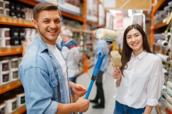 Young couple buying repair tools in hardware store. Male and female customers look at the goods in diy shop