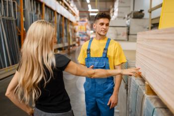Consultant and female customer in hardware store. Seller in uniform and woman in diy shop, chipboard choice, shopping in building supermarket