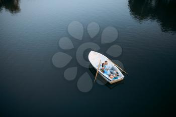 Love couple lying in a boat on silent lake, top view. Romantic meeting, boating trip, man and woman walking along the lake