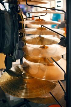 Copper drum cymbals on showcase in music store, closeup view, nobody. Assortment in musical instrument shop, professional equipment for musicians and performers