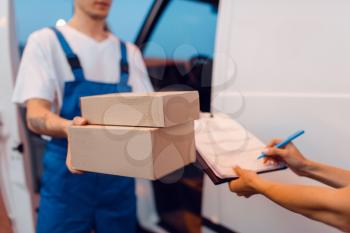 Deliveryman in uniform gives parcel to female recipient at the car, delivery service. Man holding cardboard package near the vehicle, male deliver and woman, courier or shipping job