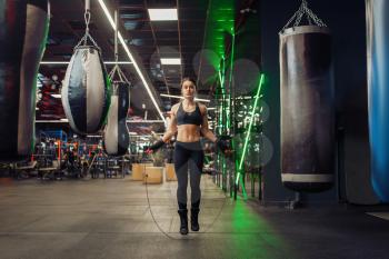 Woman jumps with a skipping rope, boxing training. Female boxer in gym, girl kickboxer in sport club, fitness workout