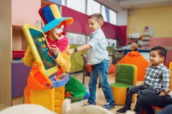 Funny clown with joyful children play in the alphabet on board. Birthday party celebrating in playroom, baby holiday in playground. Childhood happiness, childish leisure