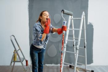 Surprised young woman makes home repair, happy female person doing appartment renovation, room decoration renovating