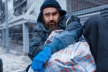 Male bearded beggar lies on city street. Poverty is a social problem, homelessness and loneliness, alcoholism and drunk addiction, urban lonely