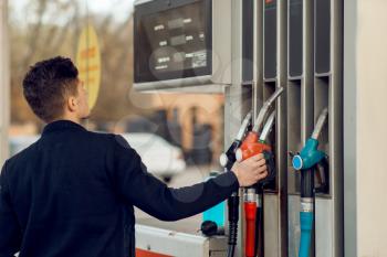 Man takes the gun on gas station, closeup view, fuel filling concept. Petrol fueling, gasoline or diesel refuel service