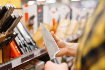 Young man choosing kitchen knife in houseware store. Male person buying home goods in market, guy in kitchenware supply shop